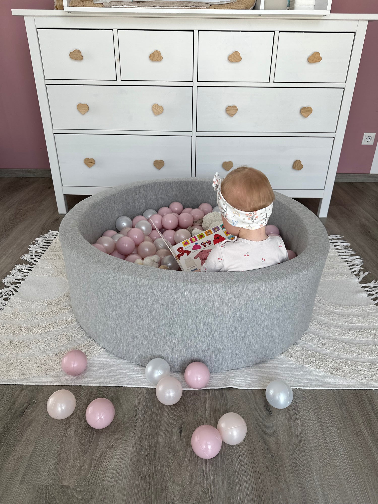 Kind liest in hellgrauem Bällebad